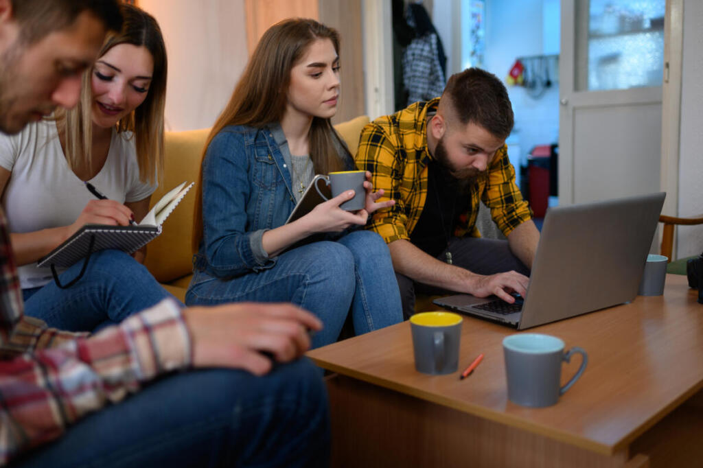 Gruppo di giovani al laptop con snack e caffè