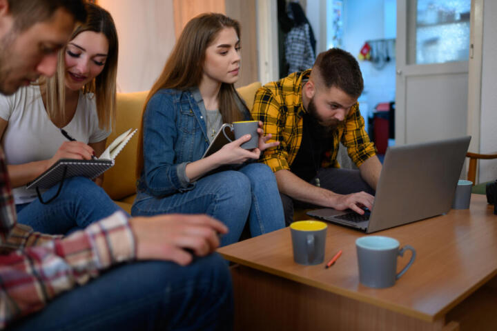 Gruppo di giovani al laptop con snack e caffè
