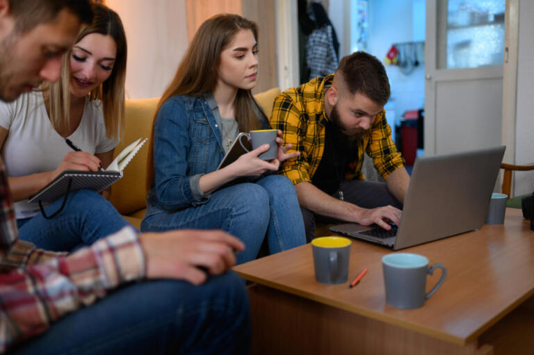 Gruppo di giovani al laptop con snack e caffè